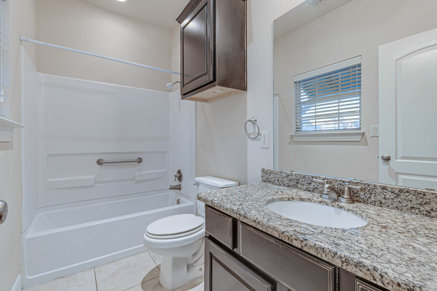 A clean, bright bathroom with dark wood cabinets.