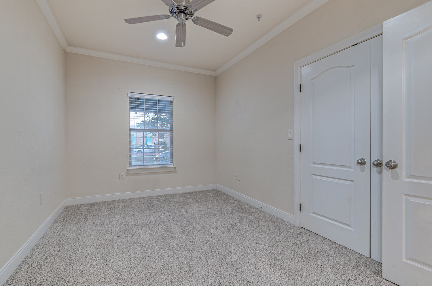 Carpeted bedroom with ceiling fan and large window.