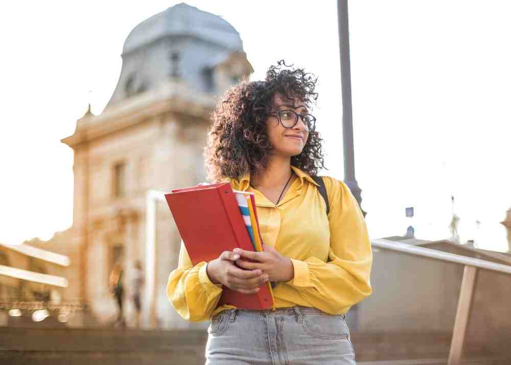 A woman at a university holding her books.